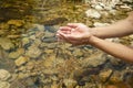 Closeup shot of a persons hand picking up water from a lake