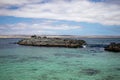 Closeup shot of a piece of rocky land in a blue ocean near the coastline