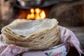 Closeup shot of a pile of corn tortillas with a mud stove in the background