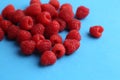 Closeup shot of a pile of fresh raspberries on a blue background Royalty Free Stock Photo