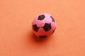 Closeup shot of a pink and black toy soccer ball on an orange background Royalty Free Stock Photo