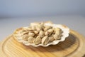 Closeup shot of pistachios in a seashell-shaped vase on a round wooden plate Royalty Free Stock Photo