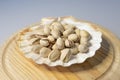 Closeup shot of pistachios in a seashell-shaped vase on a round wooden plate Royalty Free Stock Photo