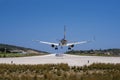 Closeup shot of a plane landing in a small airport with houses and forests on the background Royalty Free Stock Photo