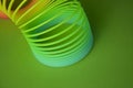 Closeup shot of plastic rainbow magic spring toy isolated on green background with copy space