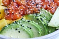 Closeup shot of a poke salad with salmon, avocado, mango, edamame, crispy onion and sesame seeds
