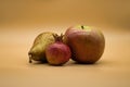 Closeup shot of pomegranate, apple, and a pear isolated on a peach background