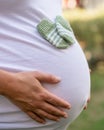 Closeup shot of a pregnant female with a pair of cute baby mittens on her belly