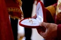 Closeup shot of a priest holding a heart-shaped box containing two gold wedding bands Royalty Free Stock Photo
