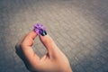 Closeup shot of a purple flower in the hands of a woman over the tiles of the ground