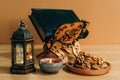 Closeup shot of the Quran with a rosary on wooden stand with Ramadan lantern, candle and walnuts