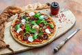 Closeup shot of raw vegan pizza next to an old pepper mill with dried peppercorns on a wooden board Royalty Free Stock Photo