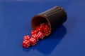 Closeup shot of red dice falling out of a leather dice cup on a blue background Royalty Free Stock Photo