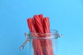 Closeup shot of the red licorice sticks in a glass container on a blue background Royalty Free Stock Photo