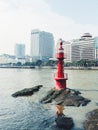 Closeup shot of a red lighthouse with a cityscape on the background Royalty Free Stock Photo