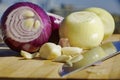 Closeup shot of red onion, white onion, and garlic with a kitchen knife on wooden chopping board Royalty Free Stock Photo
