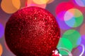 Closeup shot of a red sparkly Christmas tree ball against the colorful bokeh lights Royalty Free Stock Photo