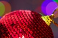 Closeup shot of a red sparkly Christmas tree ball against the colorful bokeh lights Royalty Free Stock Photo