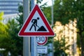 Closeup shot of a red triangular traffic sign of "working on road" with a blur background