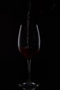 closeup shot of red wine pouring into glass from bottle isolated on black background Royalty Free Stock Photo