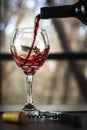 Closeup shot of red wine pouring in glass isolated on blurry background