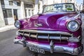 Closeup shot of a retro style purple car rolling through the streets of colorful Habana in Cuba