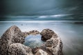 Closeup shot of rock filled with in the middle in the sea under a blue cloudy sky Royalty Free Stock Photo