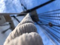 Closeup shot of a rope hanging from the top of a boat under the blue blurry sky Royalty Free Stock Photo