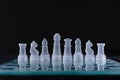 Closeup shot of a row of crystal chess pieces on a glass board on black background Royalty Free Stock Photo