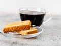 Closeup shot of rusk in saucer with defoused black coffee on background Royalty Free Stock Photo