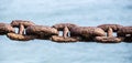 Closeup shot of a rusty old interlinked chain on a blue background Royalty Free Stock Photo