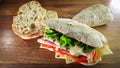 Closeup shot of a sandwich with cheese, ham, tomatoes, lettuce, and pieces of bread on the table Royalty Free Stock Photo