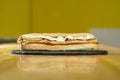 Closeup shot of a sandwich with mayonnaise on a black round board on a wooden table