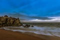 Closeup shot of a sandy rocky beach and the blue sea on a cloudy day Royalty Free Stock Photo