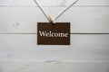 Closeup shot of a sign with welcome written on it and a white wooden background Royalty Free Stock Photo