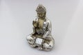 Closeup shot of a silver Buddha statuette on a white surface Royalty Free Stock Photo