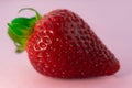 Closeup shot of a single fresh ripe strawberry on a pink background Royalty Free Stock Photo