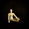 Closeup shot of a sitting wooden puppet isolated on the empty dark blurred background Royalty Free Stock Photo