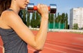 Closeup shot of slender sporty woman doing exercises with the dumbbells at the stadium. Empty space Royalty Free Stock Photo