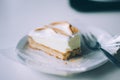 Closeup shot of a sliced cheesecake on a round white plate with a silver fork Royalty Free Stock Photo