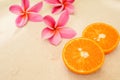 Closeup shot of sliced oranges next to pink plumerias Royalty Free Stock Photo