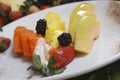 Closeup shot of sliced pineapple, papaya, melon, strawberries, and blackberries on a plate