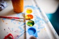 Closeup shot of a small watercolor palette and a brush on a painting table for children