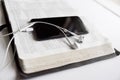 Closeup shot of a smartphone and headphones on an opened bible with a blurred background Royalty Free Stock Photo
