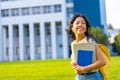 Closeup shot of a smiling Southeast Asian female student holding textbooks in her arm