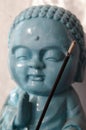 Closeup shot of smoking incense stick with buddha statue in the background Royalty Free Stock Photo