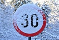 Closeup shot of a 30 speed limit indicator by covered with snow