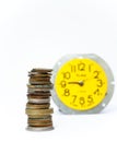 Closeup shot of stack of mixed rusty coins with yellow alarm clock in the blur background Royalty Free Stock Photo