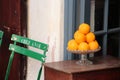 Closeup shot of a stack of oranges on the table with a chair near it Royalty Free Stock Photo