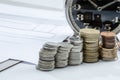 Closeup shot of stacks of coins near a clock